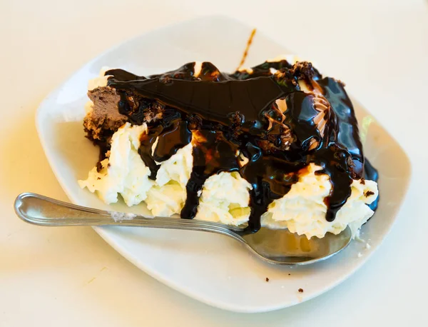 Tranche de gâteau au chocolat savoureux servi sur une assiette blanche avec crème fouettée — Photo
