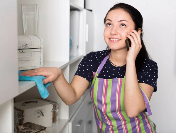 Chica limpiando estantes y hablando por teléfono — Foto de Stock