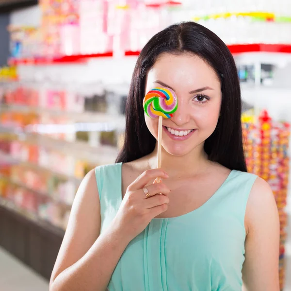微笑的女孩在商店里吸棒棒糖 — 图库照片