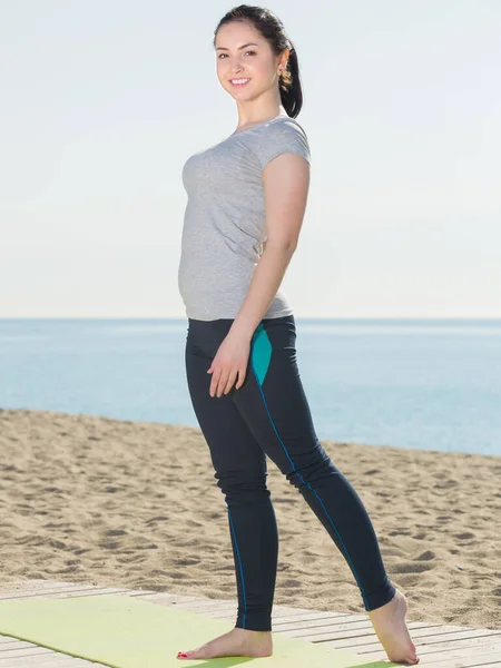 Encantadora mujer entrenando en la playa por mar — Foto de Stock