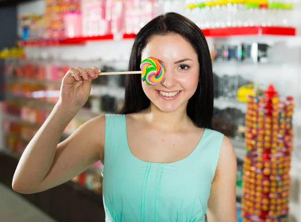 Usmívající se dívka sání lízátko v obchodě — Stock fotografie