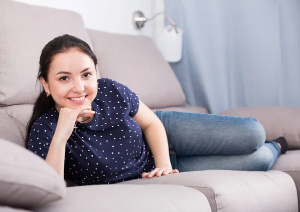 Lächelnde Brünette auf Sofa liegend — Stockfoto