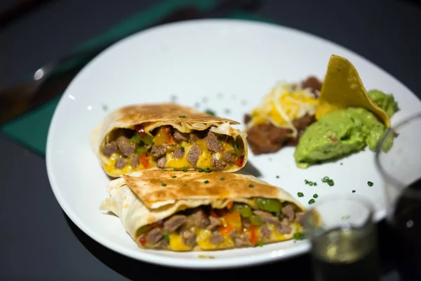 Mexicaanse burrito geserveerd met guacamole op bord — Stockfoto