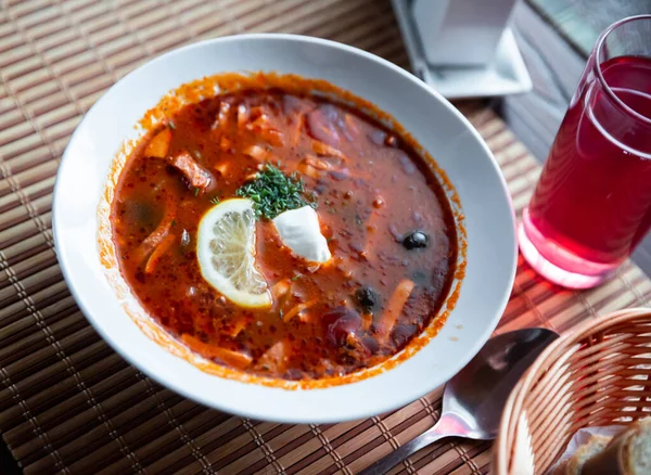 Deliziosa zuppa di carne solyanka sul brodo servita con panna acida ed erbe aromatiche — Foto Stock