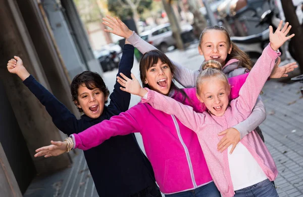Fyra glada barn leker utan föräldrar på trottoaren i modern stad — Stockfoto