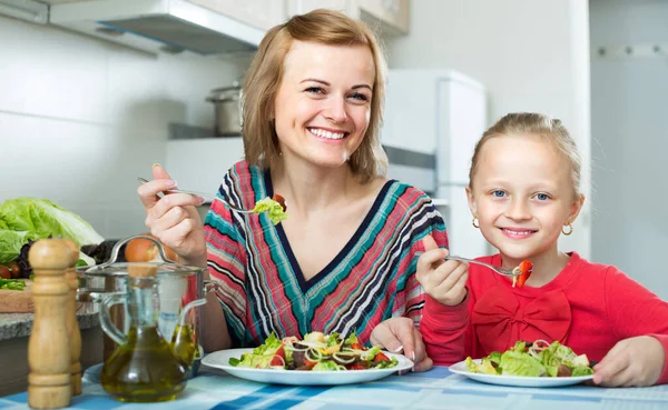 Mulher e menina comendo na cozinha. — Fotografia de Stock