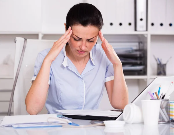 Denkende vrouw in kantoor zittend aan tafel — Stockfoto