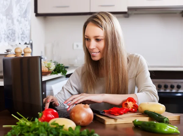 Smiling woman cooking with laptop — Stock Photo, Image