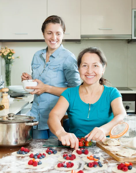 Mulheres sorrindo fazendo tortas com bagas — Stockfoto