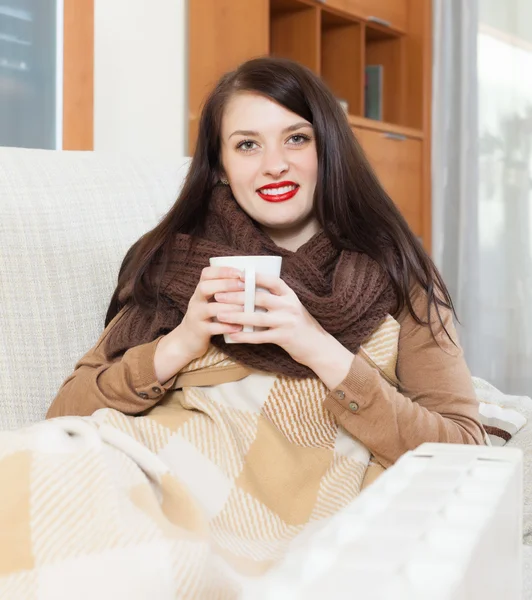 Ragazza con tazza vicino riscaldatore elettrico — Foto Stock