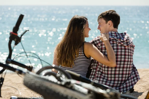 Menina e seu namorado na praia perto de bicicletas — Fotografia de Stock