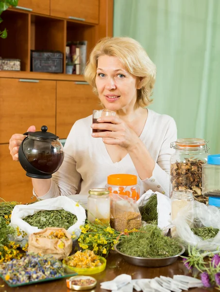 Femme mature assise à table avec des herbes — Photo