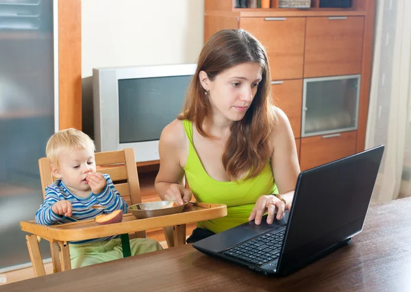 使用笔记本电脑和婴儿的女人 — 图库照片