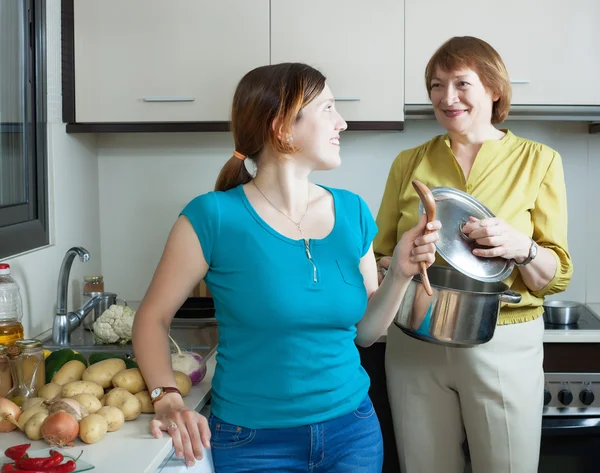 Mulher e sua mãe madura cozinhar comida — Fotografia de Stock