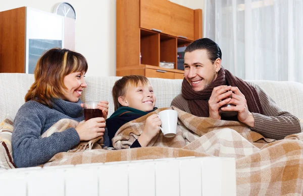 Parents and  son warming near warm heater — Stock Photo, Image