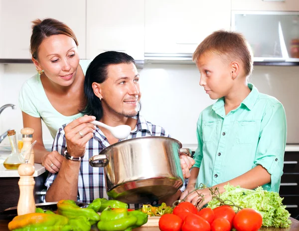 Glad familj på tre matlagning lunch — Stockfoto