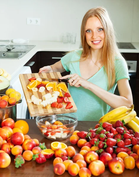 Blonde woman cutting fruits for salad — Stock Photo, Image