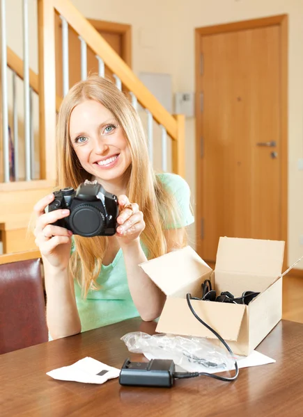 Jovem mulher na mesa com nova câmera digital — Fotografia de Stock