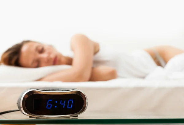 Relógio despertador contra mulher dormindo — Fotografia de Stock