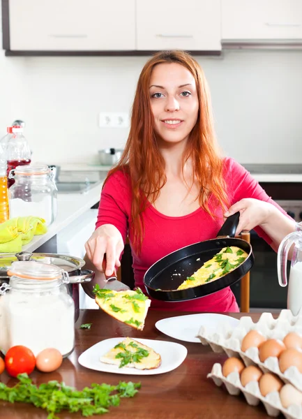 家庭の台所で調理されたオムレツを持つ女性 — ストック写真