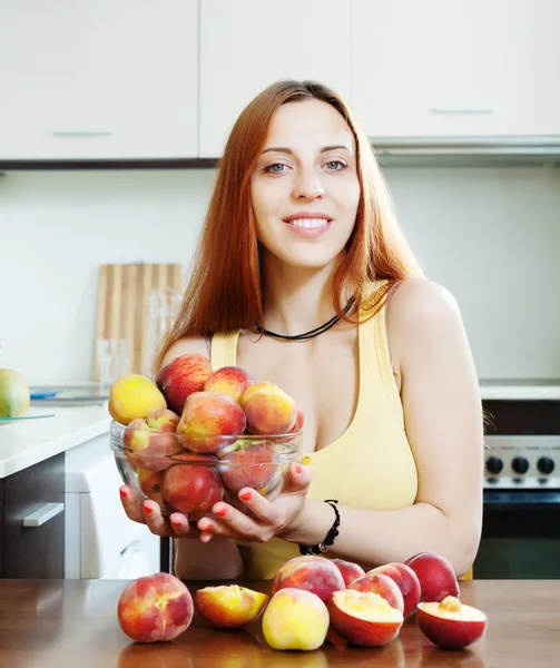 Mooi meisje in geel houden perziken — Stockfoto