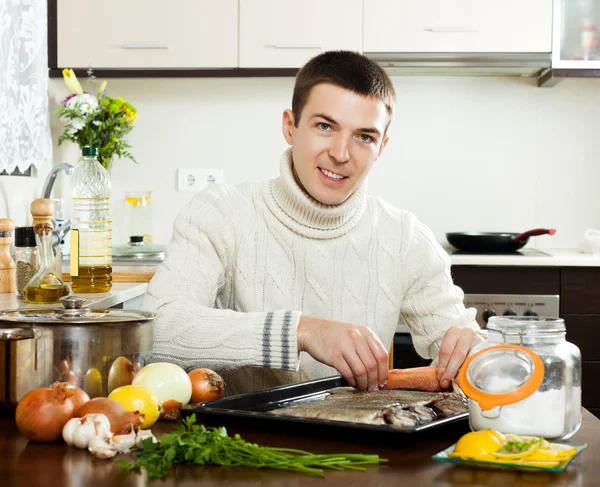 Ragazzo mettendo il pesce in teglia — Foto Stock