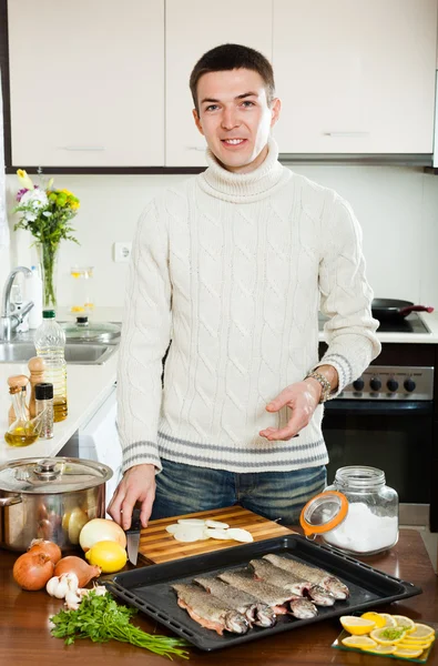 Hombre guapo cocinando pescado en bandeja para hornear —  Fotos de Stock