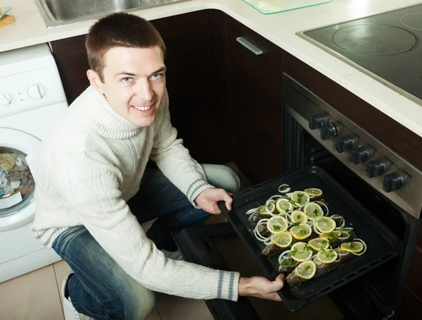 Bel homme mettre du poisson dans le four à la cuisine — Photo