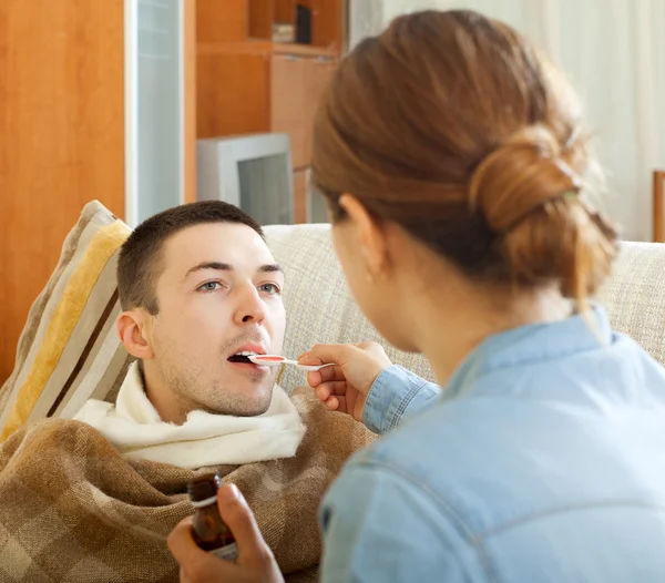 Girl giving syrup to diseased man — Stock Photo, Image