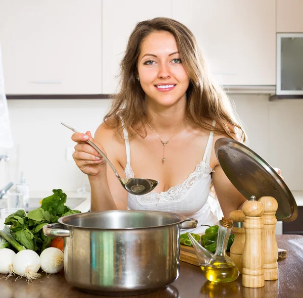 Vrouw koken soep in keuken — Stockfoto