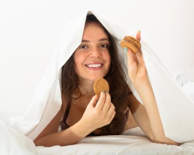 Woman eating cookies in bed clipart
