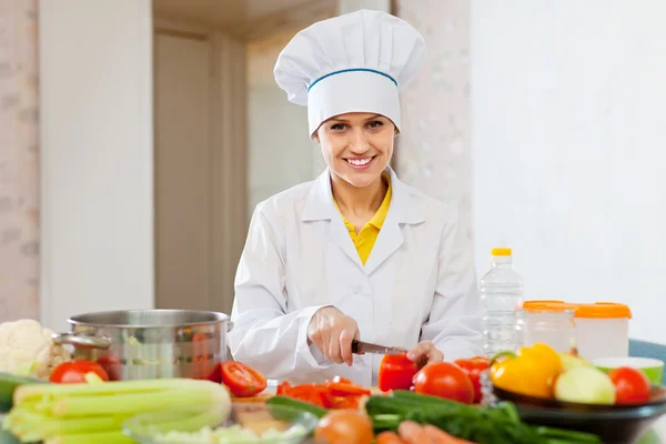 Cozinheira sorrindo funciona com tomate e outros vegetais — Fotografia de Stock