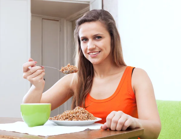 Woman eats buckwheat porridge with spoon — Stock Photo, Image