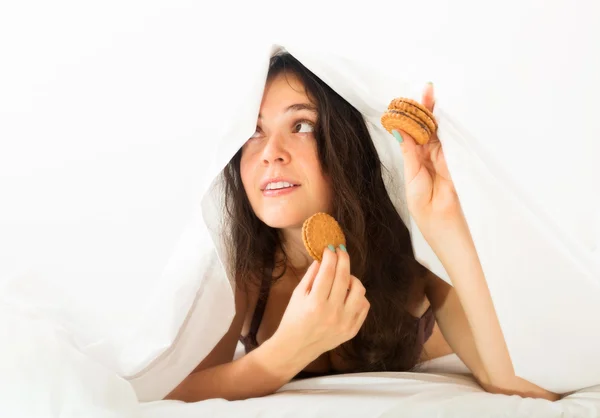 Frau isst Kekse im Bett — Stockfoto