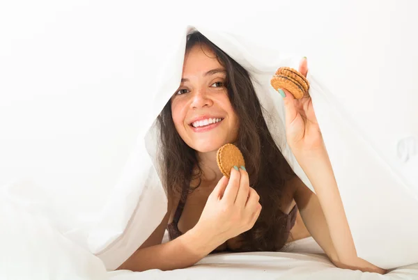 Девочка ест печенье в постели — стоковое фото