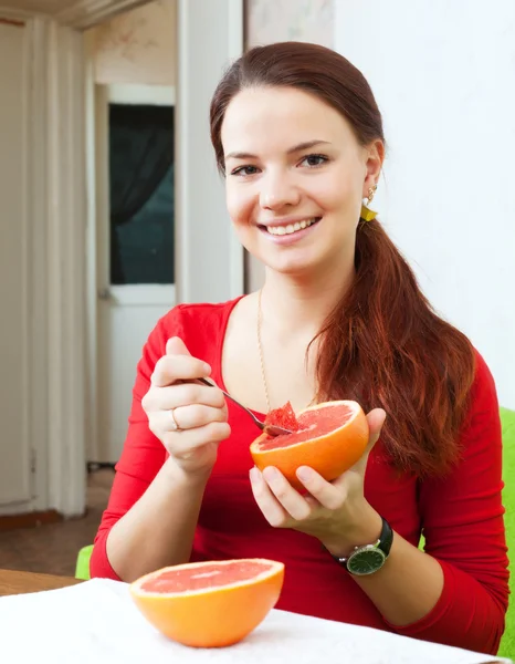 Mulher bonita em vermelho come toranja — Fotografia de Stock