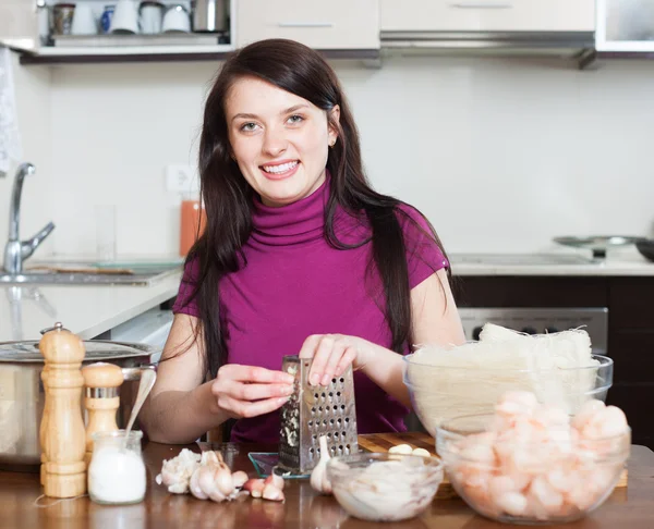 Vrouw raspen knoflook op rasp voor noedels met zeevruchten — Stockfoto