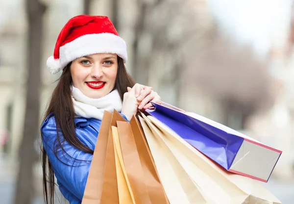 Femme heureuse en chapeau de Père Noël avec des achats — Photo