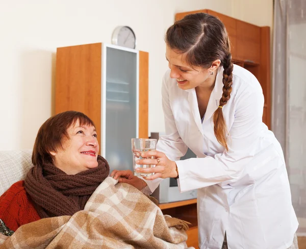 Nurse in uniform caring for happy mature woman — Stock Photo, Image