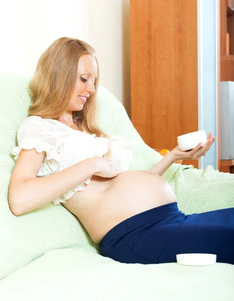 Pregnant woman uses cosmetic cream — Stock Photo, Image