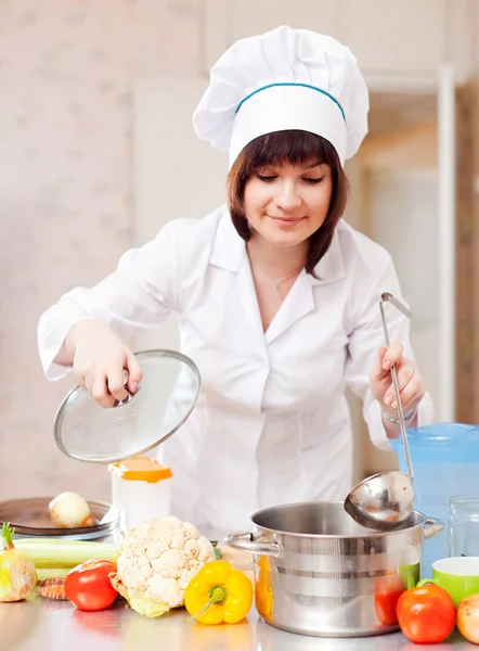 Vrouw in toque koks in keuken koken — Stockfoto