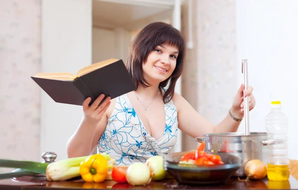 Jeune femme au foyer cuisine avec livre de cuisine — Photo