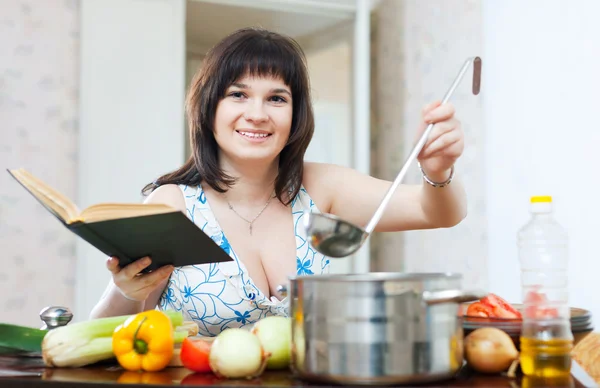Positive woman cooking with cookery book — Stock Photo, Image