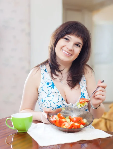 Femme mange de la salade de légumes sur le canapé à l'intérieur — Photo