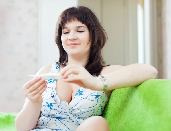 Ordinary woman looks by thermometer — Stock Photo, Image