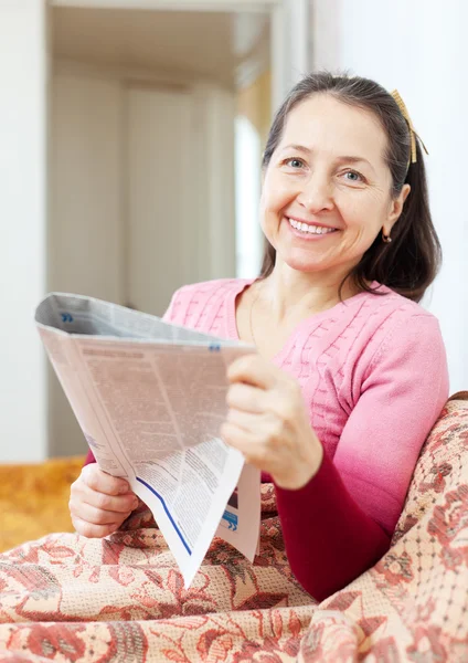 Smiling mature woman reads newspaper — Stock Photo, Image