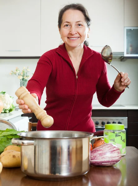 Woman adding seasoning into soup pan — Stock Photo, Image