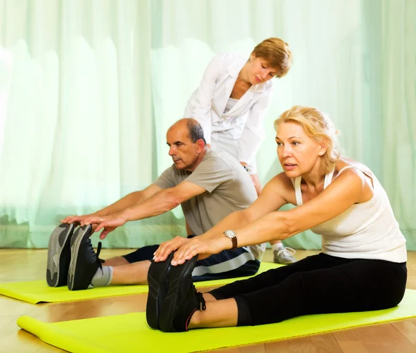 Yoga instructor showing asana to mature couple — Stock Photo, Image