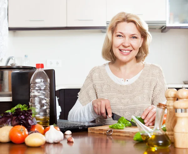 Femme au foyer avec ordinateur portable dans la cuisine à la maison — Photo