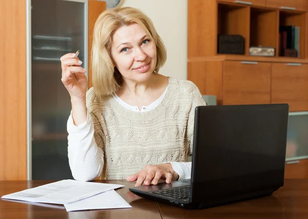 Volwassen vrouw met laptop en financiële documenten — Stockfoto